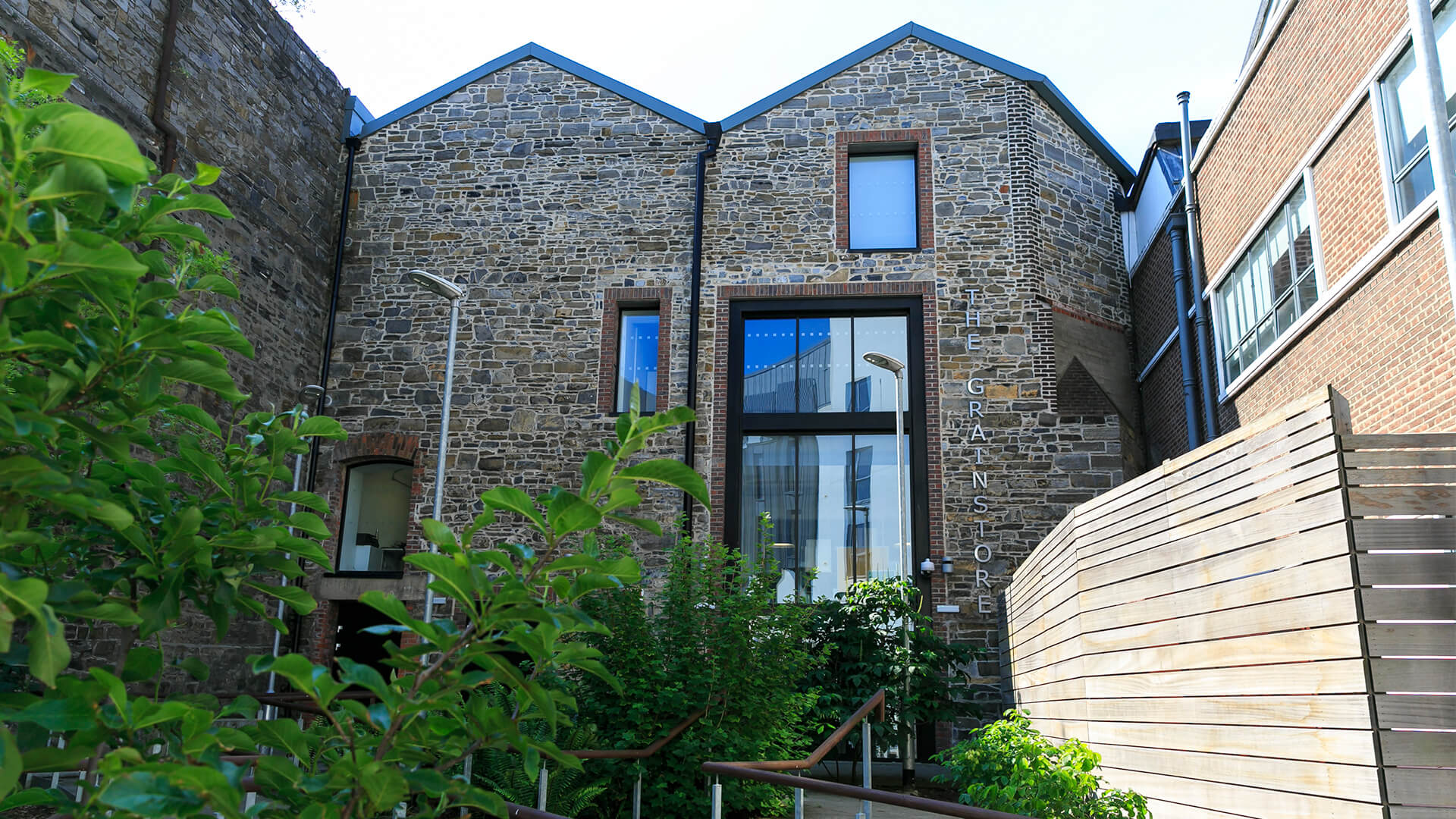 A shot of the stone Grainstore building with foliage in the foreground